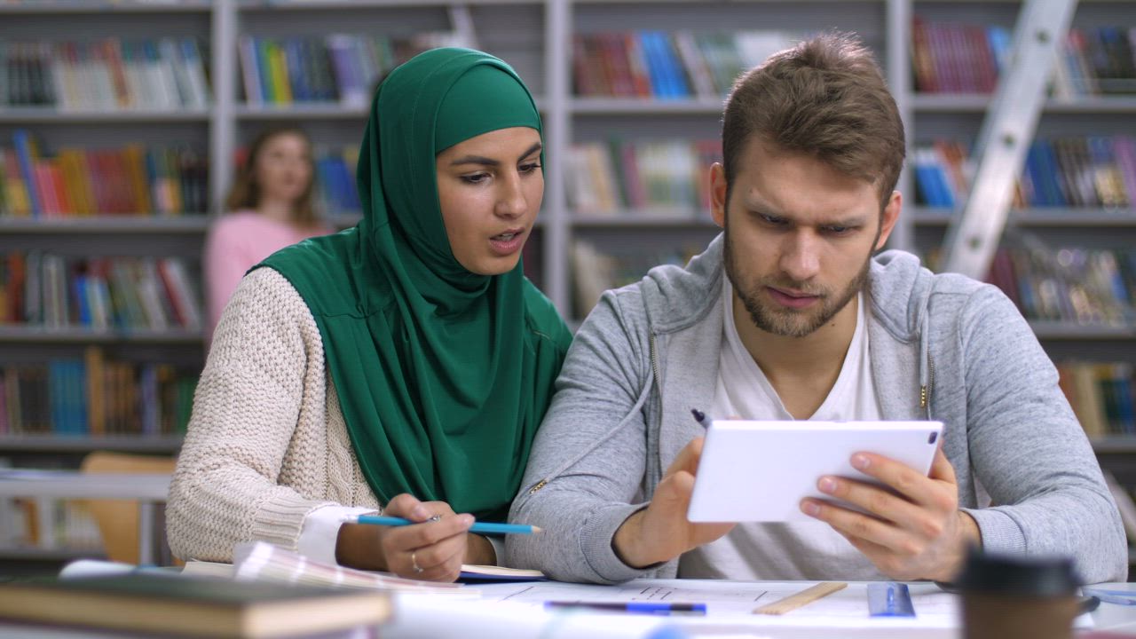 Students researching using a tablet at library - Free Stock Video
