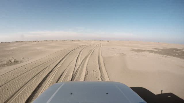 Front view of a car driving through the desert.