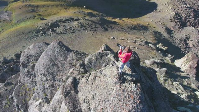 Photografer in the top of a rock in the mountains.