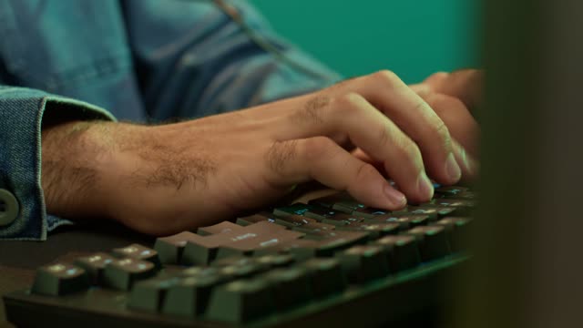 Close-Up of Hands on LED Keyboard.